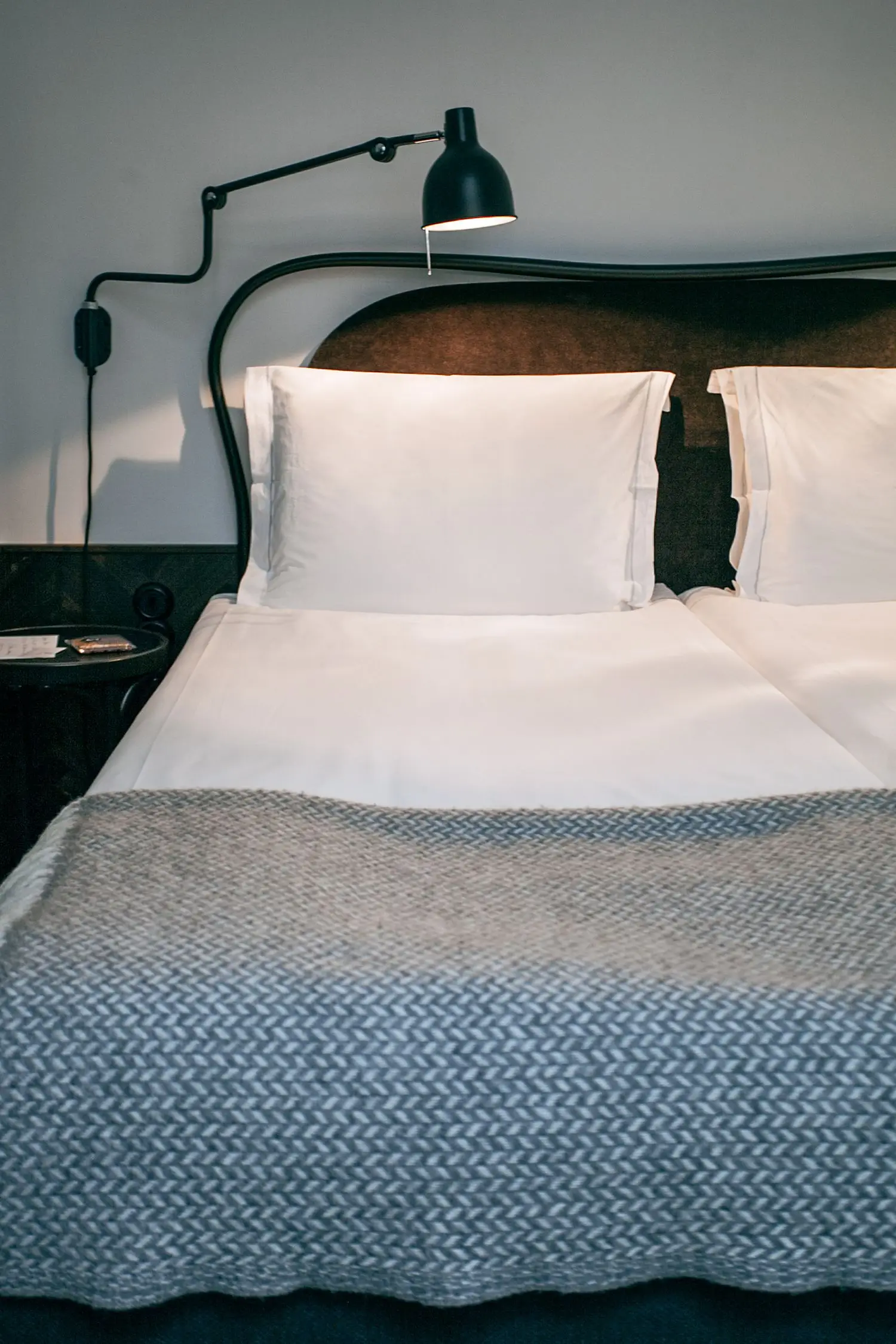 Rauhallinen hotellivuode tummalla seinäpinnalla